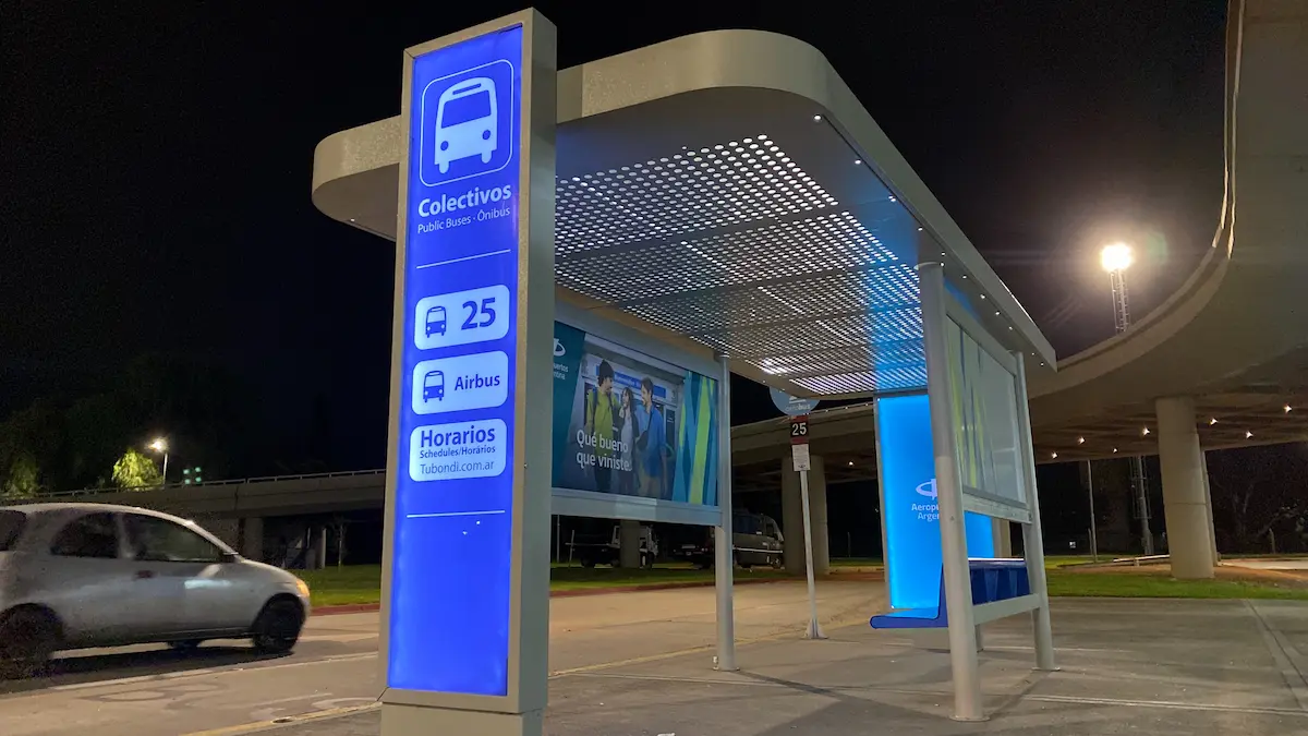 Refugio urbano con senal de colectivos iluminada en azul
